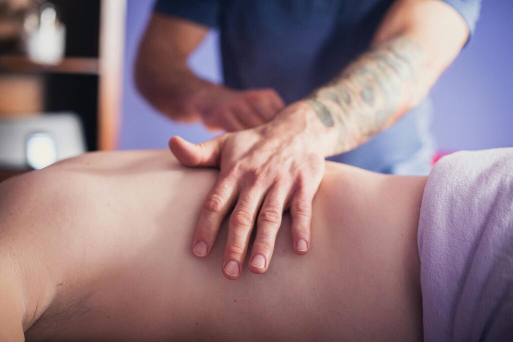 Close-up of hands performing a soothing back massage in a calming spa environment, promoting relaxation and wellbeing.